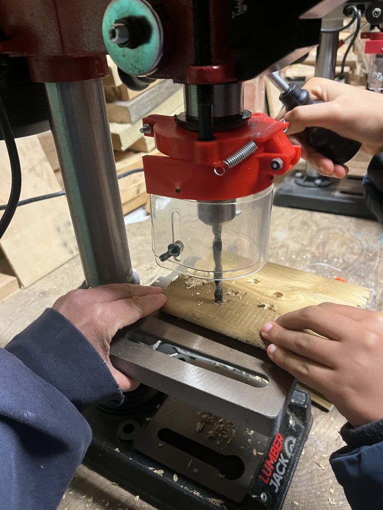 Scouts using the pillar drill to make lots of insect holes 