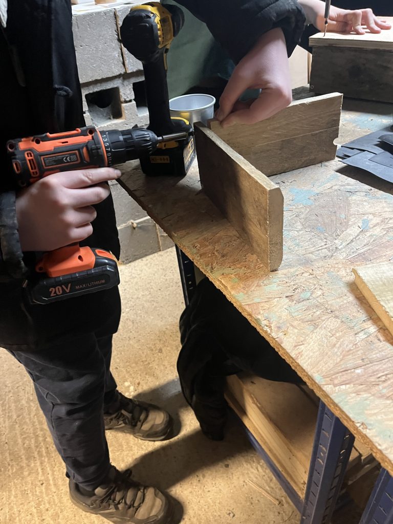 Scouts using an electric drill to piece together the rectangle boxes